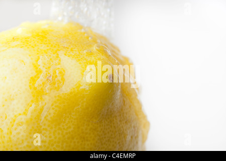 A fresh yellow lemon being washed with water Stock Photo