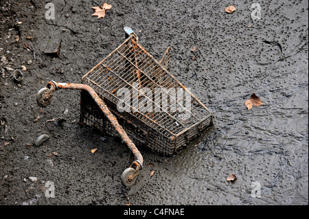 Shopping trolley lodged in mud at bottom of canal, exposed when canal drained Stock Photo