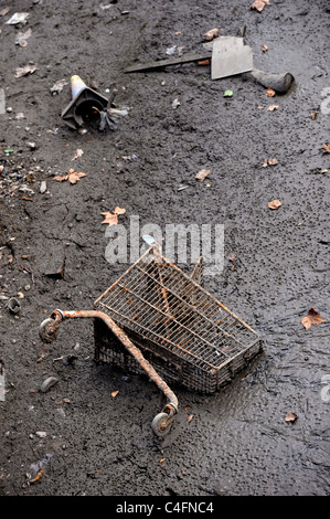 Shopping trolley lodged in mud at bottom of canal, exposed when canal drained Stock Photo