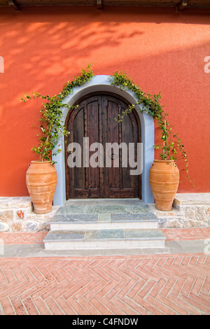 Wooden textured door with decorative pots against red wall Stock Photo