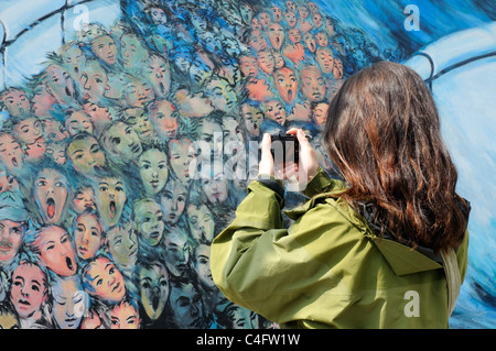 A woman taking pictures of the paintings on the Berlin Wall at the East Side Gallery Stock Photo