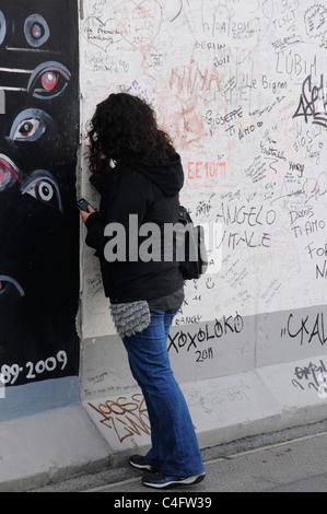 A girl writing on the Berlin Wall