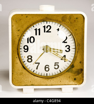 Ancient clock with three arrows showing 3:20. Old white gold alarm clock. Stock Photo