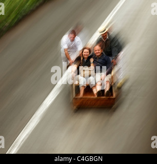 Couple enjoying the famous wicker basket toboggan run from Monte into Funchal, Madeira. Stock Photo