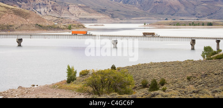 Two big rig diesel trucks driving over a bridge on Blue Mesa Reservoir in Southern Colorado Stock Photo
