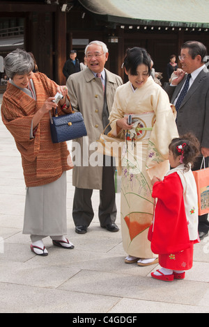 Three generations, with grandmother taking picture of granddaughter dressed up for Shichi-Go-San (7-5-3) at Meiji-jingu shrine. Stock Photo