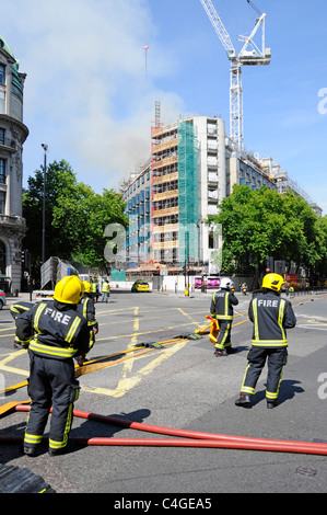 Firemen attending hoses to fight major fire at Marconi House beyond in Aldwych London Stock Photo