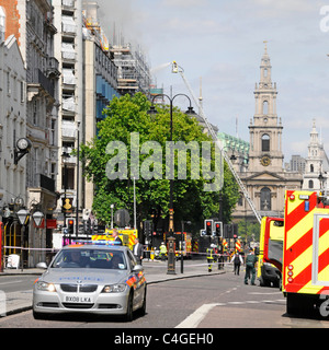 St Mary Le Strand Church tower stands beyond firefighter on telescopic access platform at major fire in Marconi House Aldwych Stock Photo
