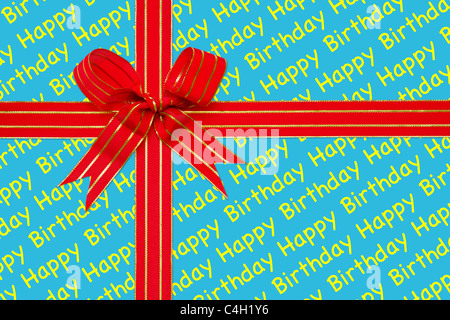 Photo of a red and gold ribbon tied in a bow on Happy Birthday wrapping paper. Stock Photo