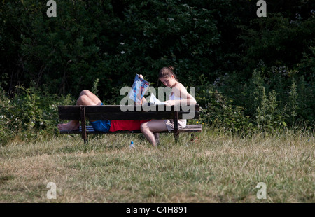 A couple having a relaxing time on a park wooden bench, Parliament Hill, London, England, UK, GB. Stock Photo