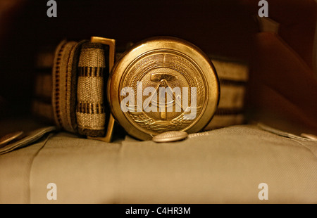 The national emblem of the former GDR stamped on a belt buckle which takes part of the uniform of an ex Stasi officer. Stock Photo