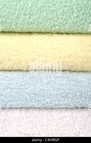 Different shades of towels stacked on each other on a white background Stock Photo