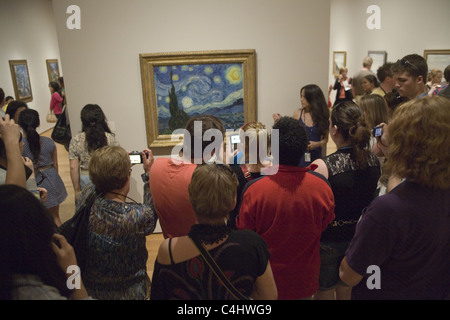 Visitors crowd around 'The Starry Night' one of the best known paintings in the world, by Vincent van Gogh at MOMA, NY City. Stock Photo