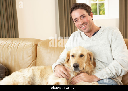 Young man with dog sitting on sofa Stock Photo