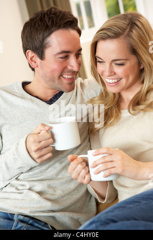 Young couple sitting and relaxing on sofa with cup in hand