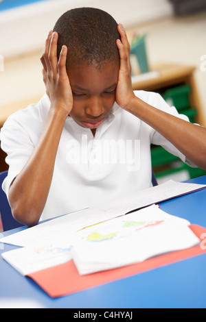 Stressed Schoolboy Studying In Classroom Stock Photo