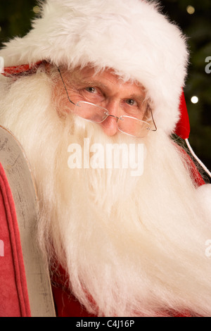 Santa Claus Sitting In Armchair In Front Of Christmas Tree Stock Photo