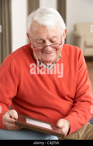 Senior Man Looking At Photograph In Frame Stock Photo