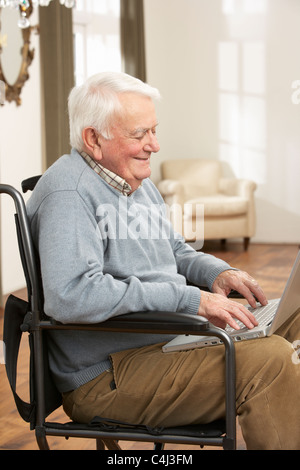 Disabled Senior Man Sitting In Wheelchair Using Laptop Stock Photo