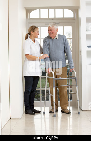 Carer Helping Elderly Senior Man Using Walking Frame Stock Photo