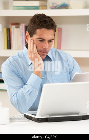 Worried Looking Man Working From Home Using Laptop Stock Photo