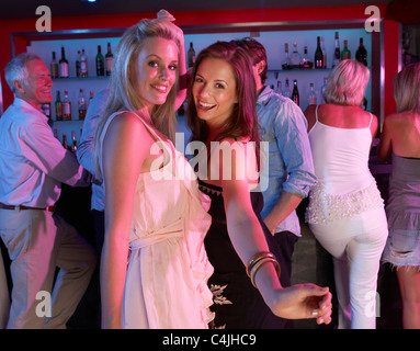 Two Young Women Having Fun In Busy Bar Stock Photo