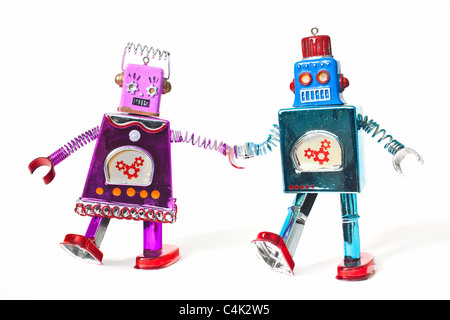 Toy robots holding hands and walking as a couple. Stock Photo