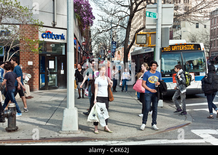 diverse pedestrians crowd corner of 9th Avenue & 42nd Street on a warm spring day in Hells Kitchen Neighborhood New York City Stock Photo