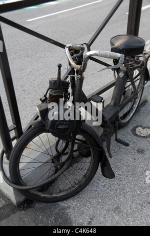Old French Velosolex moped locked to fence by port in Nice France Stock Photo
