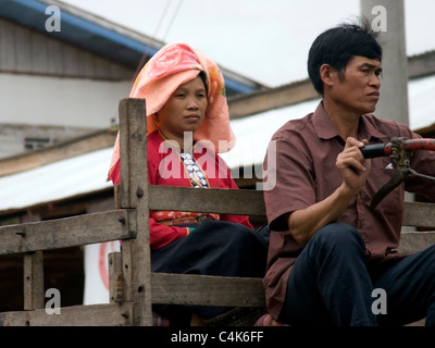 A man and a woman who are hilltribe subsistence farmers are riding on a tractor in rural communist Laos. Stock Photo