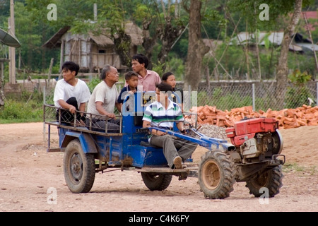 A group of subsistence farmers are riding on a tractor in rural communist Laos. Stock Photo