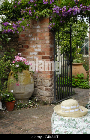 Portrait image of a typical English country garden with wall,garden gate table and straw hat Stock Photo