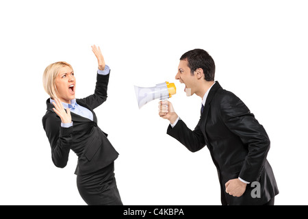 An angry businessman yelling via megaphone to a scared businesswoman Stock Photo