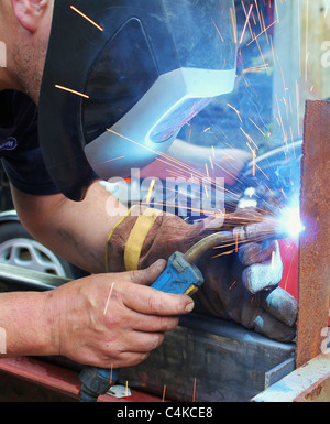 Arc welder wearing welding mask with welding sparks Stock Photo
