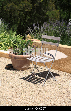 Traditional french folding garden chair in domestic garden in Provence France mistrale wind blowing cushion windy day Stock Photo