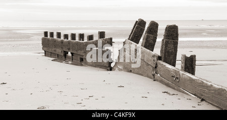 Broken groyne on beach at low tide Stock Photo