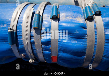 Many hose clamps tightened around form an ad hoc repair to leaking pipe Stock Photo