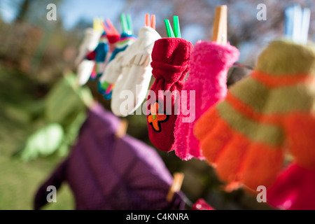 Colorful kid gloves hanging on a washing line in the backyard of an apartment house, Czech Republic. Stock Photo