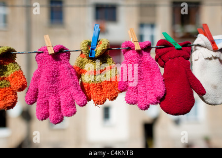 Colorful kid gloves hanging on a clothes line in the backyard of an apartment house, Czech Republic. Stock Photo