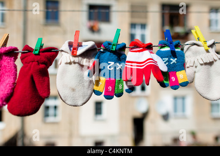 Colorful kid gloves hanging on a washing line in the backyard of an apartment house, Czech Republic. Stock Photo