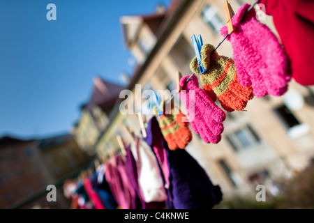 Colorful kid gloves hanging on a clothes line in the backyard of an apartment house, Czech Republic. Stock Photo