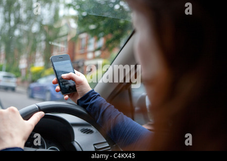 Woman texting on phone whilst driving. Stock Photo