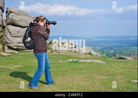 A photographer taking pictures of the view that surrounds Haytor rocks in Dartmoor National Park. Stock Photo