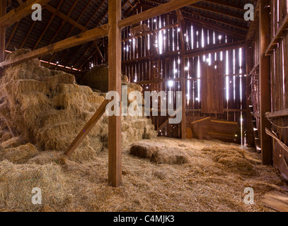 HDR image of an old Barn with the sun streaming from outside and straw and hay on the floor of the hayloft Stock Photo