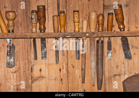 Verschiedene Werkzeug zur Holzbearbeitung hängen an einer Holzwand | Various tools for woodworking hanging on a wooden wall Stock Photo
