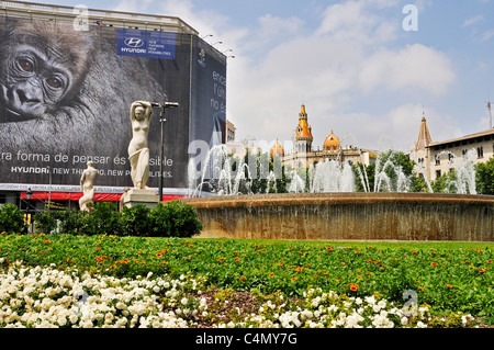 One of the many fountains in Plaça de Catalunya bordered by an advertising hoarding and modern neo-Gothic buildings, Barcelona Stock Photo