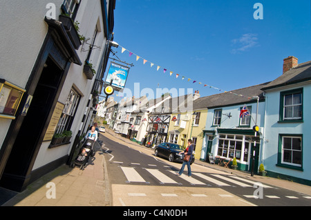 Horizontal wide angle view of a typical British village High Street decorated with bunting and Union Jack flags on a sunny day. Stock Photo