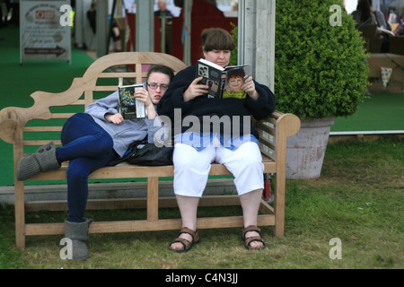 Mum's reading Jo Brand's book, daughter is reading something about love, at the Hay Literary Festival, May 2011 Stock Photo