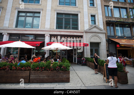 Patrons sit at the outdoor cafe of The Red Rooster restaurant in the neighborhood of Harlem in New York Stock Photo