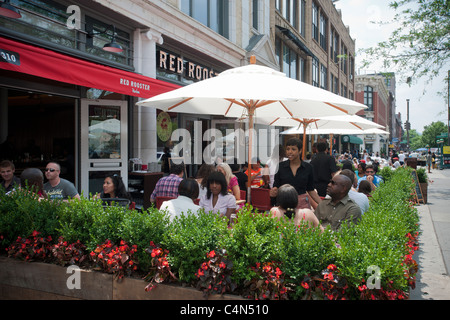 Patrons sit at the outdoor cafe of The Red Rooster restaurant in the neighborhood of Harlem in New York Stock Photo